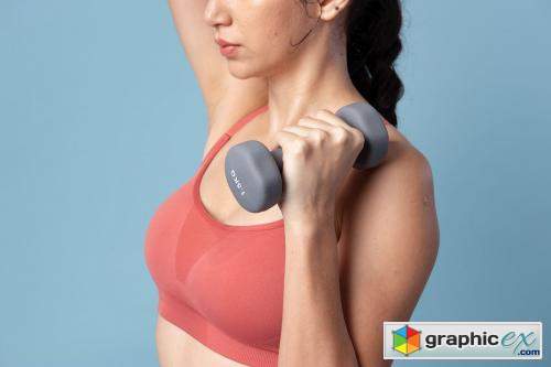 Sporty woman lifting dumbbells on blue background