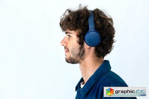 Cheerful man listening to music through headphones in a white background